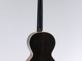 an acoustic guitar hanging from a string on a white wall