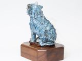 sculpture of a dog sitting on a wooden base on a white background