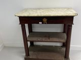 an old wooden table with a marble top in a white room