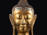 une tête de Bouddha dorée sur fond noir, avec un fond noir