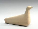 a wooden bird that is sitting on a white surface