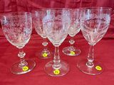six verres à vin vides sont alignés sur une nappe rouge