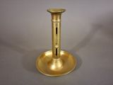 a gold candle holder on a table with a gray background