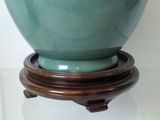a green vase sitting on a wooden stand on a table