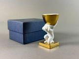 a small statue of a child holding a gold cup