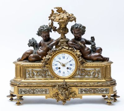 a gold clock with two cherensils on top of it