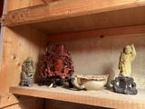 une étagère sur laquelle sont disposées de nombreuses statuettes et des bols