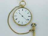 a small gold pocket watch with a chain around it