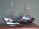 une petite maquette de bateau posée sur une table en bois