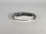 une assiette en argent avec une poignée, posée sur un fond blanc