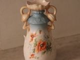 a small blue vase with flowers on it sitting on a shelf