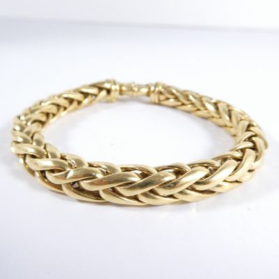 gros plan d'un bracelet en or sur une surface blanche