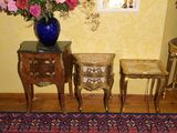 un vase de fleurs posé sur une table, à côté de deux tables d'appoint