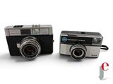 two cameras sitting next to each other on a white surface