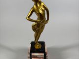 gold statue of a man standing on a marble base with his hands on his hips