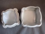 pair of white porcelain dishes with scalloped edges on a table