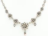 a silver necklace with pearls and a cross on a mannequin
