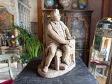 a statue of a man sitting on a chair in a room