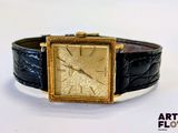 une photo d'une montre en or avec un bracelet en cuir noir