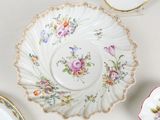 a plate with a flower design on it next to a cup and saucer