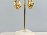 une paire de boucles d'oreilles créoles plaquées or, présentées sur un socle en marbre