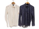 two shirts hanging on a clothes hanger on a white wall
