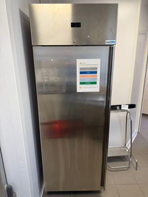 a stainless steel refrigerator in a kitchen with a sign on the door