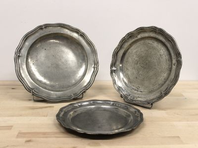 deux assiettes en argent posées sur une table en bois, avec un mur blanc en arrière-plan