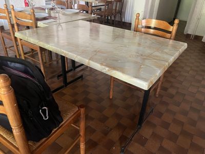 une table en marbre avec des chaises et un sac à dos posé par terre