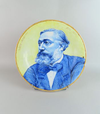 une photo d'une assiette bleue et jaune sur laquelle figure l'image d'un homme en smoking