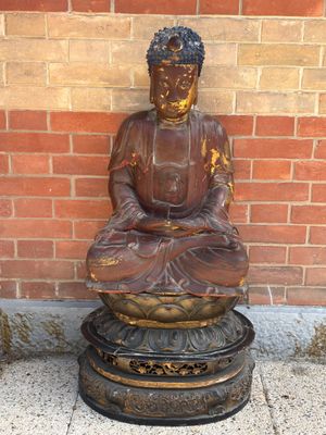 statue d'un Bouddha assis sur un socle devant un mur de briques