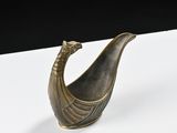 an image of a small bronze boat shaped object on a white surface