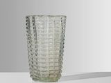 un vase en verre posé sur une table, sur fond blanc