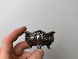 someone is holding a silver object in their hand against a white wall