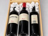 two bottles of red wine in a wooden box on a white surface