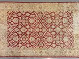 a red and beige rug with a floral design on it