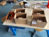 Plusieurs cartons contenant des objets divers sont posés sur une table dans une pièce.