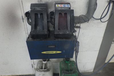 une photo d'une station-service avec deux pompes et une machine verte