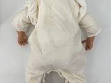 a baby doll that is laying down on a white surface
