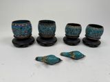 four pieces of blue pottery with gold accents on a white surface