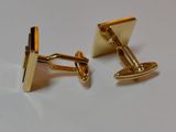 pair of gold plated cufflinks on a white surface