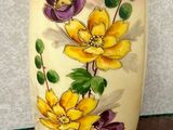 un vase avec des fleurs peintes dessus, posé sur une table