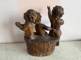 a statue of two children sitting in a wooden bucket