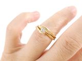 a woman ' s hand holding a gold ring with a diamond on it
