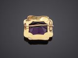 a close up of a purple stone in a gold plated broochle