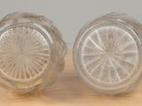 pair of clear glass salt and pepper shakers sitting on a wooden table
