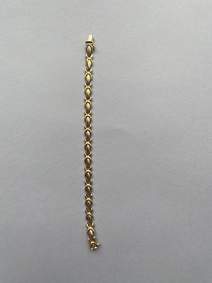 un gros plan d'un bracelet plaqué or sur une surface blanche