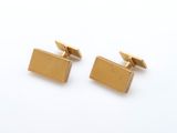 une paire de boutons de manchette en or sur fond blanc