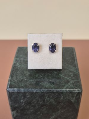 a close up of a pair of blue sapphire earrings on a marble block