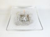 a small glass plate with a lit candle in it